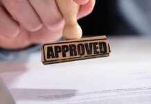 FDA vs. Kids? ZYN Flavors Survive A hand holding a wooden stamp with the word 'APPROVED' above a document