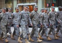 Group of soldiers marching in a military parade on a city street