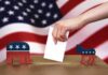 Hand casting ballot between Republican elephant and Democratic donkey