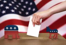 Hand casting ballot between Republican elephant and Democratic donkey