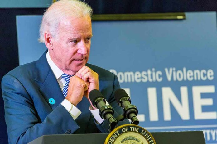 man at podium speaking with hands clasped near chin