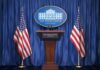 White House press podium with microphones and two American flags