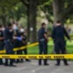 crime scene tape with police officers in a park