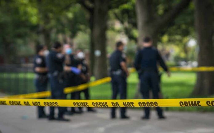 shutterstock_1814062073 crime scene tape with police officers in a park