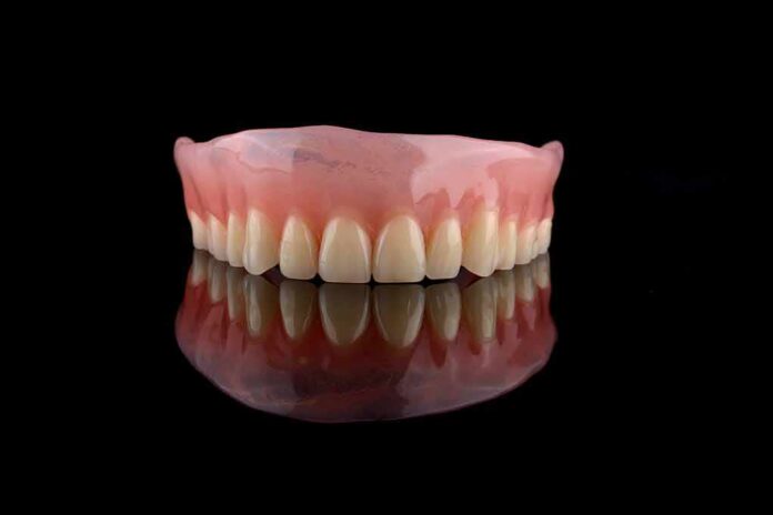shutterstock_1898636053 Upper denture on black reflective surface