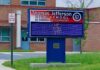 Tax Credit Twist Upends Public Schools Electronic school marquee in front of a brick high school