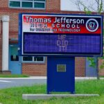 Electronic school marquee in front of a brick high school