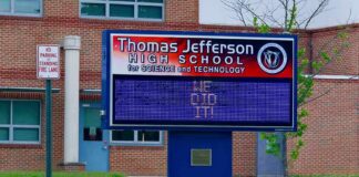 Electronic school marquee in front of a brick high school