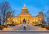 State capitol building illuminated at dusk with central dome and statue