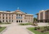 Historic capitol building with landscaped courtyard under clear blue sky