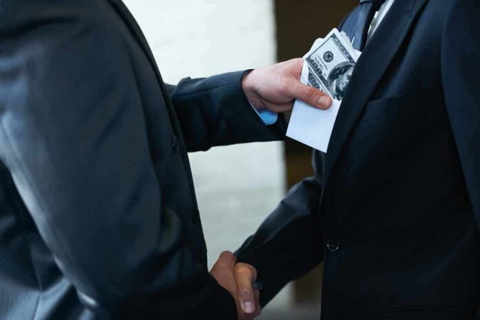 Businessmen handshake as cash is slipped into a suit pocket
