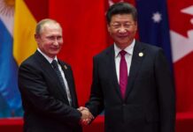 Putin–Xi Huddle Sparks- Power Play Begins two men in suits shaking hands