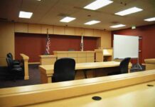 Nick Reiner Trust Fund Twist in Double-Murder Case Interior view of an empty courtroom with wooden furniture and American flags