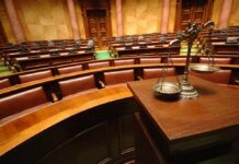 Burqa Ban Blitz—What’s Really Driving This? A courtroom with empty seats and a scale of justice in the foreground