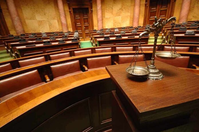 shutterstock_81191014 A courtroom with empty seats and a scale of justice in the foreground