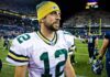 Aaron Rodgers Torches Fauci football player in white jersey and yellow beanie on the field