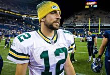 Aaron Rodgers Torches Fauci football player in white jersey and yellow beanie on the field
