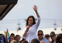 Intruder Drama At Kamala Harris’ Malibu Estate Woman speaking at outdoor event with raised hand.