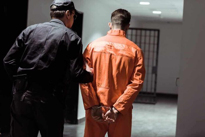 shutterstock_1030254055 Police officer escorting handcuffed inmate in orange jumpsuit