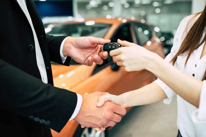shutterstock_1100968712 Hands exchanging car keys and a handshake at a dealership