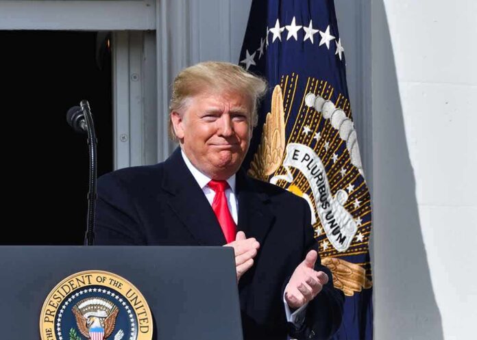 Donald Trump clapping at a podium with the presidential seal