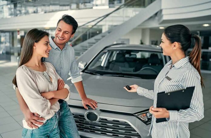 Couple with a sales representative beside a new car in a showroom