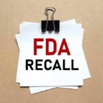 Binder clip holding stacked papers labeled FDA recall