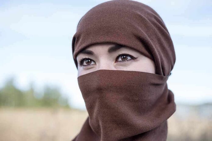 shutterstock_2029507565 Tatiana Akimova wearing a brown headscarf covering lower face outdoors