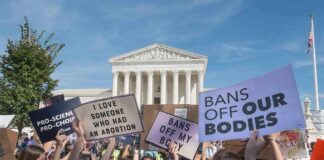 Protesters with signs in front of a neoclassical courthouse