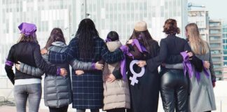 Group of women standing arm in arm with purple ribbons