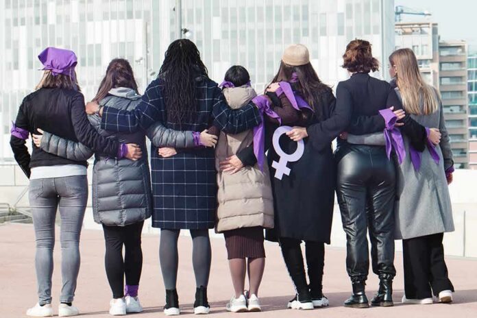 shutterstock_2103713153 Group of women standing arm in arm with purple ribbons