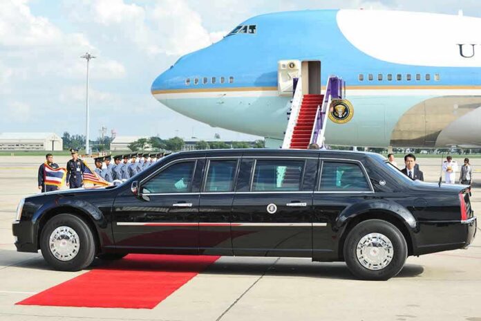 Presidential limousine beside a large blue-and-white jet on a runway