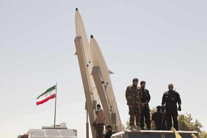 shutterstock_681421708 Soldiers stand beside large missiles at an outdoor display