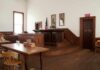 Mistrial Mayhem Sparks Juror Peril Interior of a historic courtroom with wooden furniture and an American flag