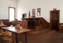 Mistrial Mayhem Sparks Juror Peril Interior of a historic courtroom with wooden furniture and an American flag