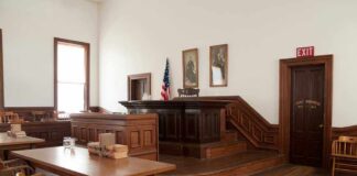 Interior of a historic courtroom with wooden furniture and an American flag
