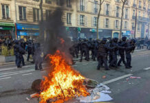 France Erupts: Students vs. Riot Police Fire burning on the street amid police presence.