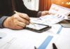 Tax Man Cornered Zuckerberg? Businessperson analyzing charts with tablet and papers