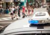 Campus Ambush Stuns University of Cincinnati police car roof light bar with blue lights near a busy crosswalk
