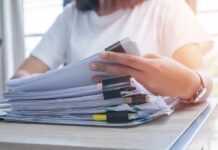 Imposter Teacher Chaos Sparks Six Felonies Person organizing a stack of documents with binder clips