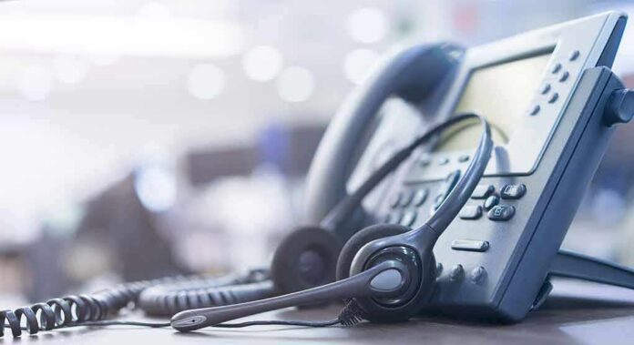 shutterstock_1248023887 Headset resting on an office desk phone