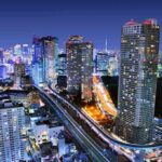 City skyline at night with illuminated skyscrapers and highways