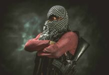 armed person with face covered crossing arms