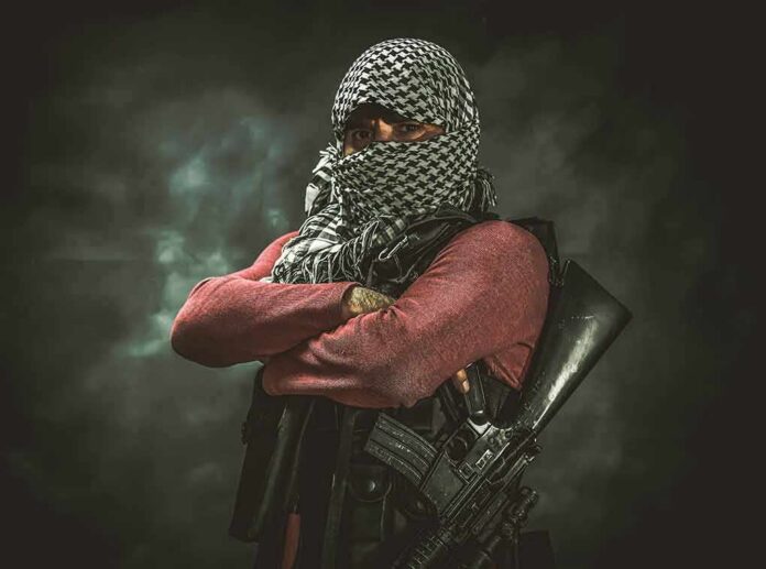shutterstock_1401389096 armed person with face covered crossing arms