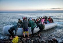 Horror Crossing Turns Deadly – Bodies Keep Washing Ashore People arriving in a crowded inflatable boat at a rocky shore