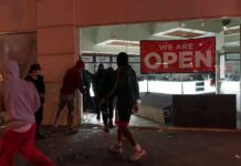 Protest Chaos Triggers Precrime Policing People outside a storefront with broken glass at night