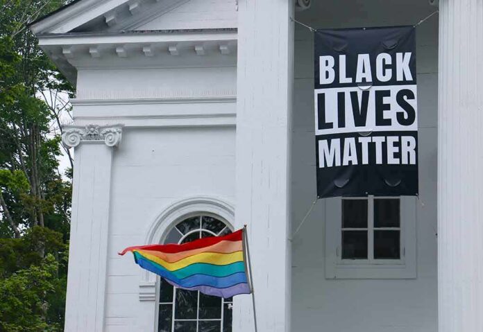 shutterstock_1769583479 Black Lives Matter banner and rainbow pride flag on white building