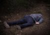 person lying face down on a forest path