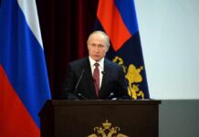 Putin Meeting: Surprise American Walks Free speaker at podium with flags in background