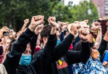 Crowd of protesters with raised fists wearing masks